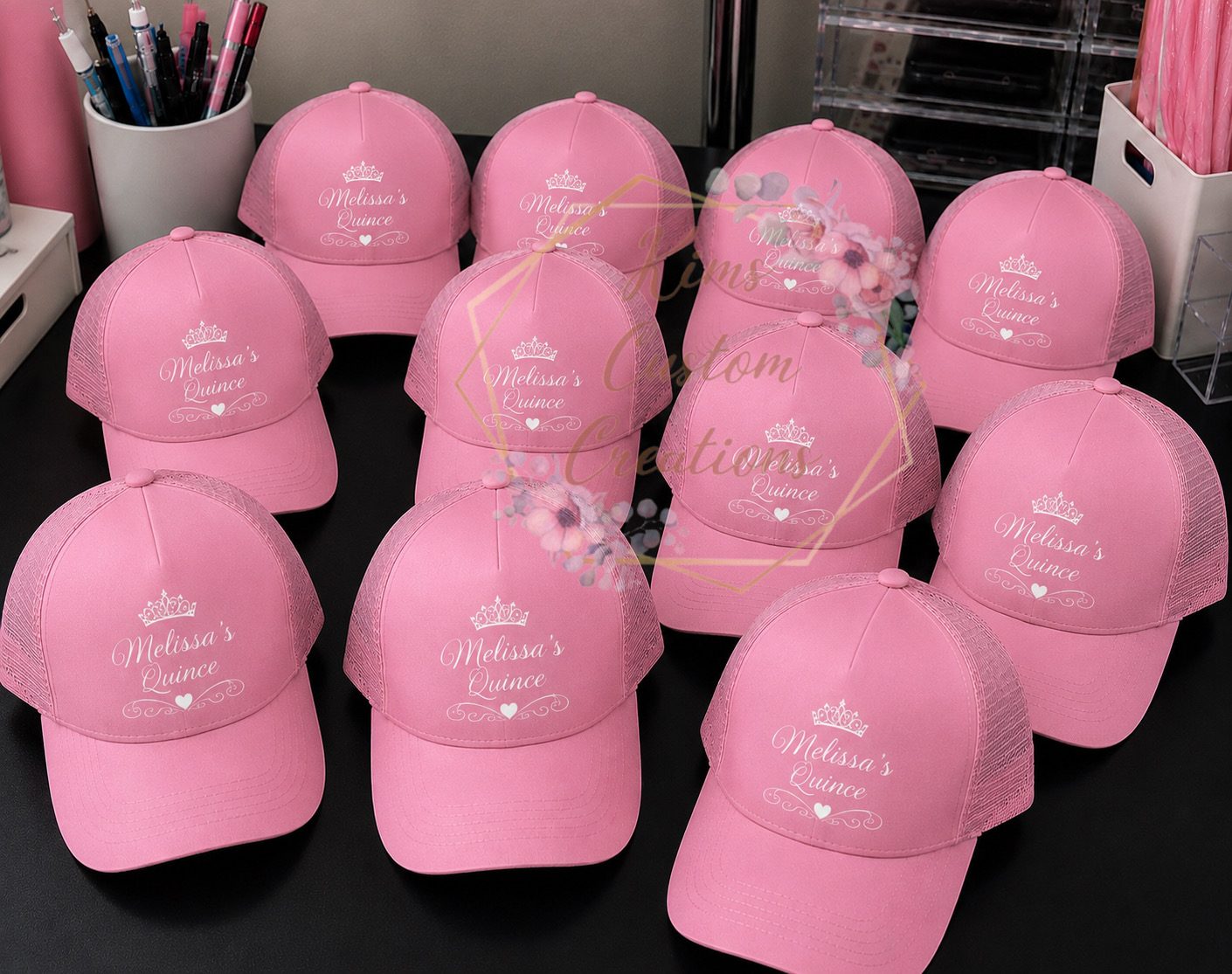 Pink trucker caps personalized with the quinceanera's name and a white tiara design